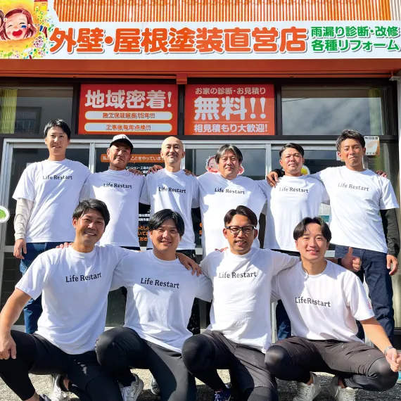 店舗の前で肩を組んだ従業員の集合写真